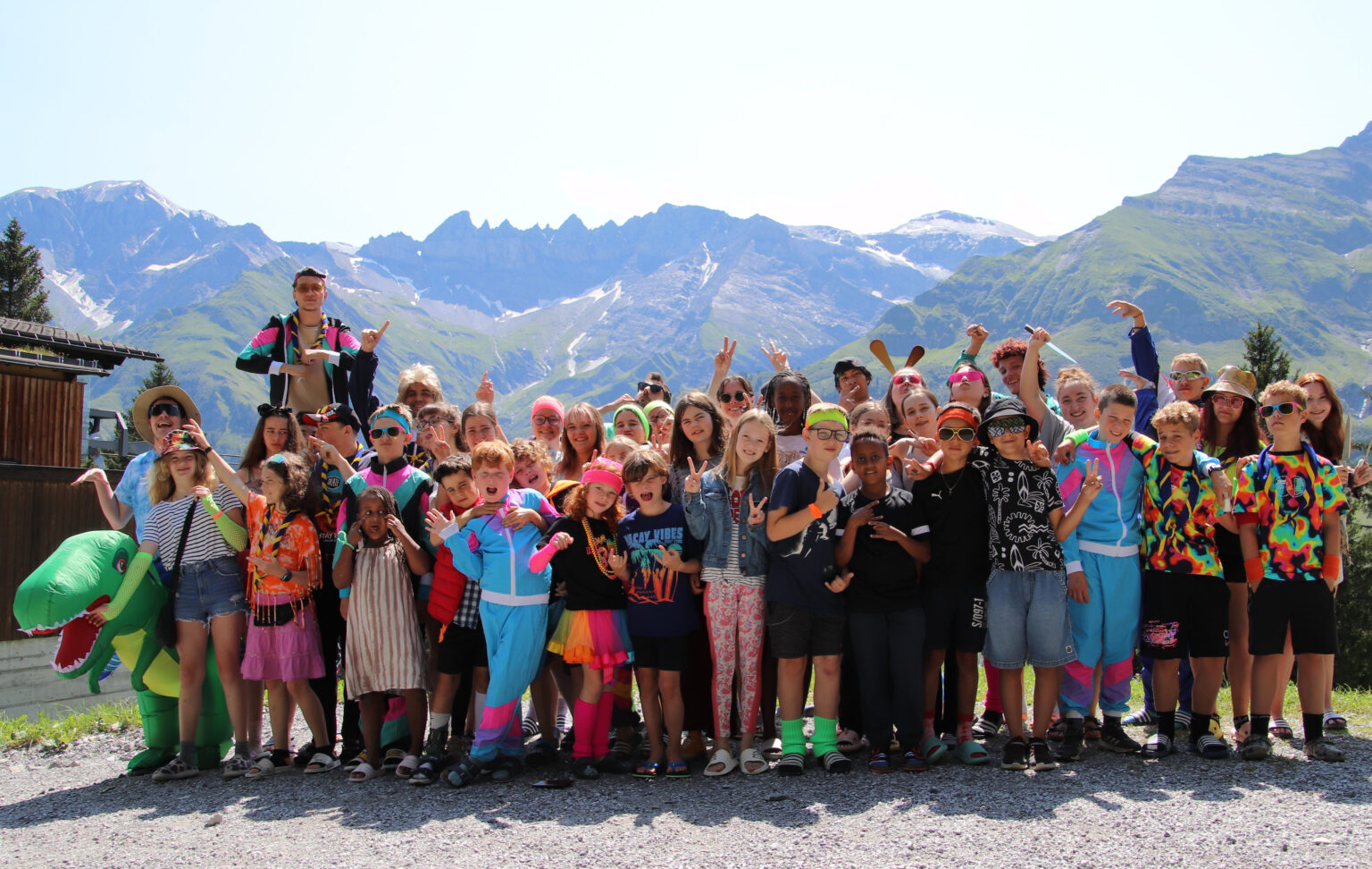 Gruppenbild der Lagerteilnehmenden in bunten Kostümen vor einer Bergkette